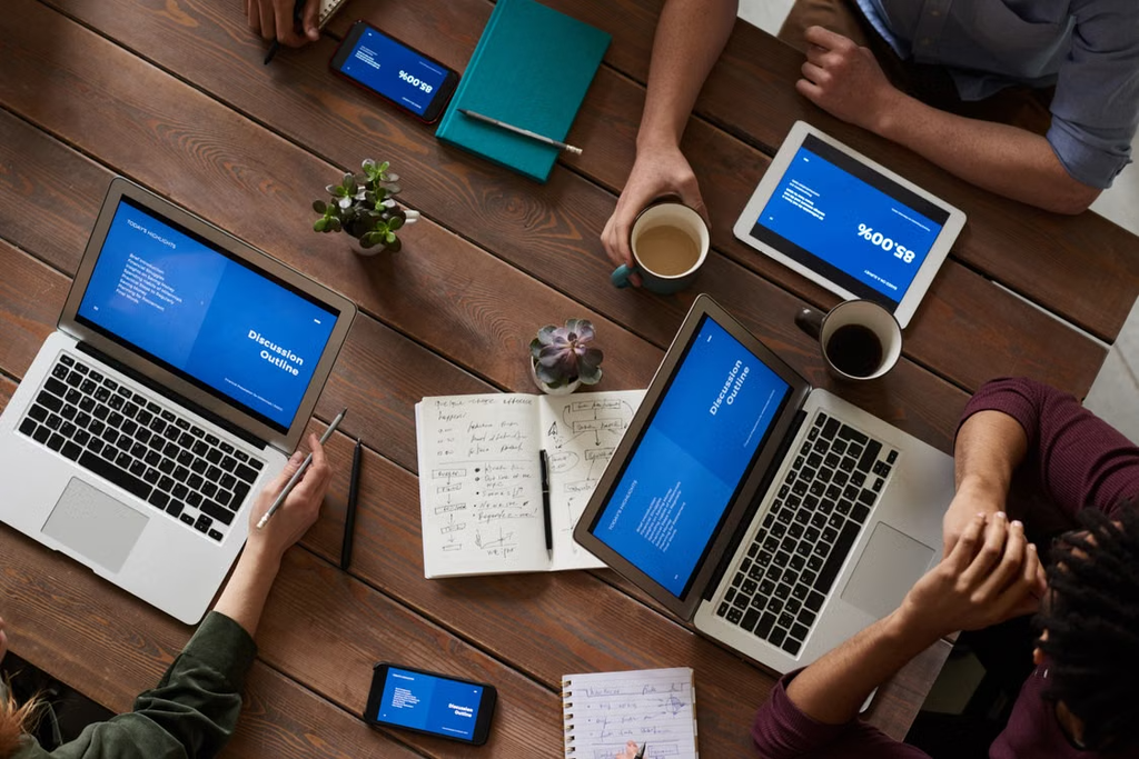 A team sat around a desk working on laptops discussing data