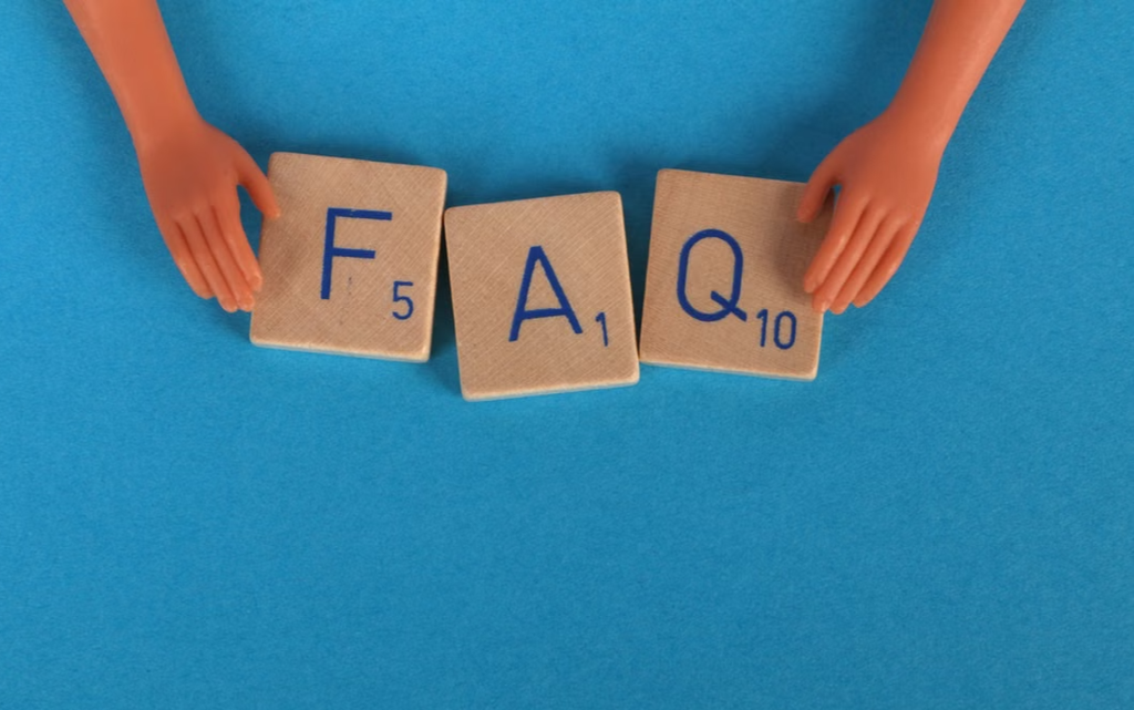 Wooden Scrabble letters against a blue background spelling out FAQ